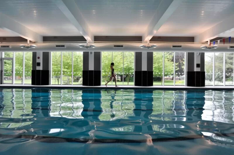 Woman in swimwear walking by The Lensbury pool at The Lensbury Resort fitness centre & gym in Teddington, all included in the cost of her Lensbury Membership.