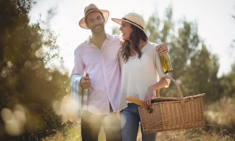 Cheerful couple carrying picnic basket