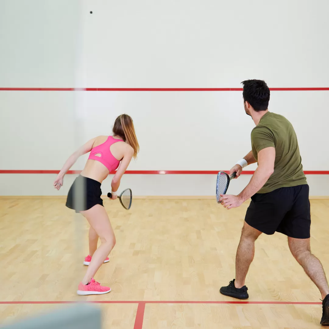 Man and woman playing squash together at The Lensbury Club