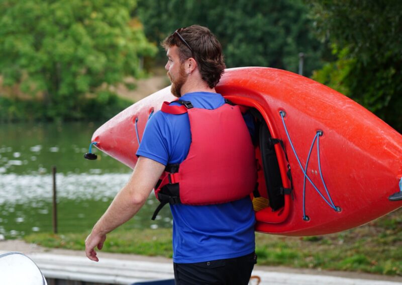 Chief Watersports Intructor at The Lensbury carrying a Kayak at the Watersports Centre
