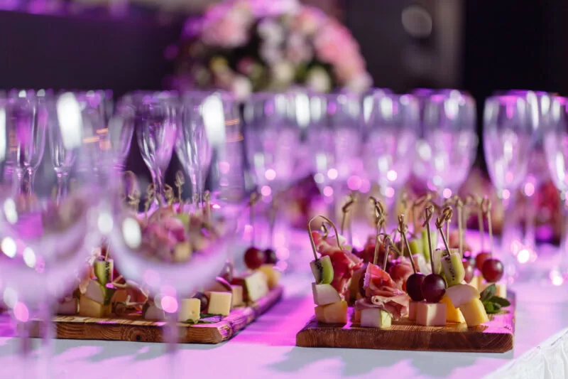 solemn happy new year banquet. Lot of glasses champagne or wine on the table in restaurant. buffet table with lots of delicious snacks. canapes, bruschetta, and little desserts on wooden plate board