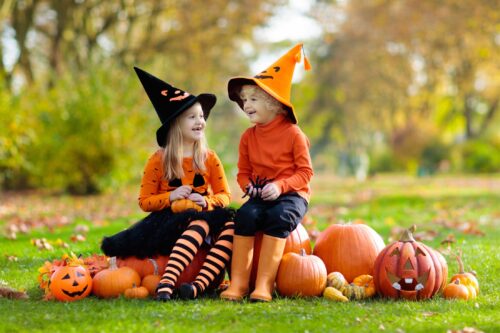 Kids dressed up for halloween with pumpkins outside