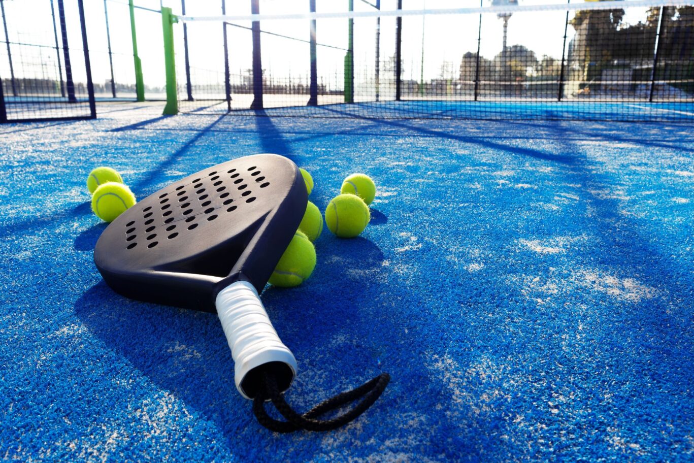 Padel racket with tennis balls on court